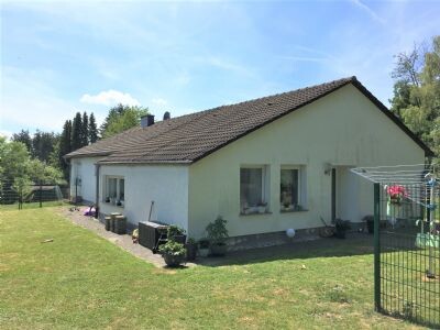 Außenansicht eines Einfamilienhauses mit hellgrüner Fassade, Ziegeldach und Garten