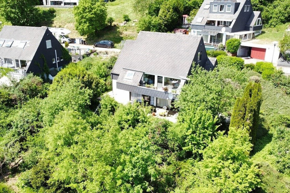 Luftaufnahme eines Einfamilienhauses mit großzügigem Garten und vielen Bäumen