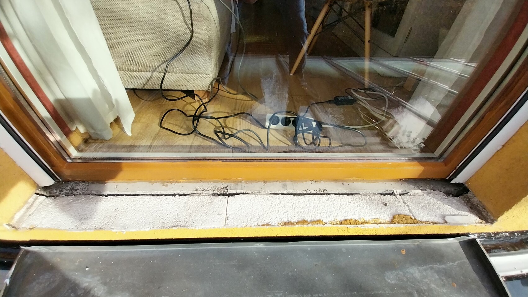 Blick auf Glastür im Eingangsbereich, Kabel auf dem Boden, Wohnzimmer im Hintergrund.