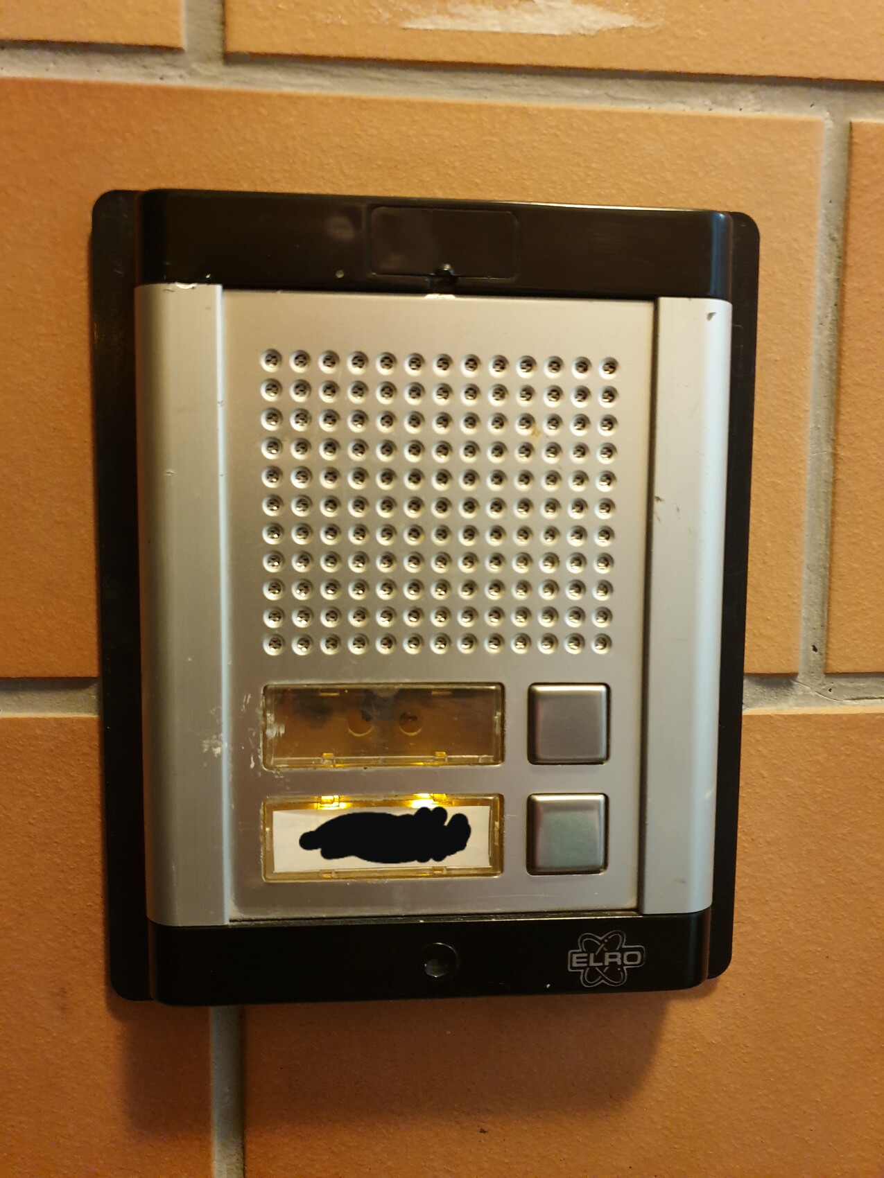 Türsprechanlage mit Lautsprecher-Gitter, Tasten und ELRO-Logo auf Ziegelwand.