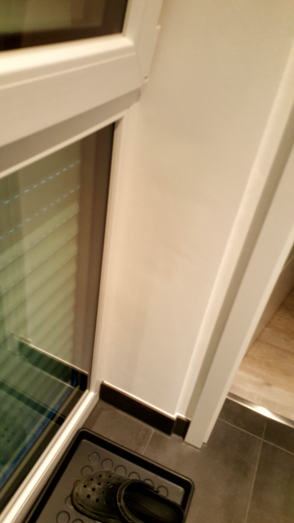 Blick auf Türrahmen und Fenster im Eingangsbereich, Schuh auf Matte vor Fliesenboden.