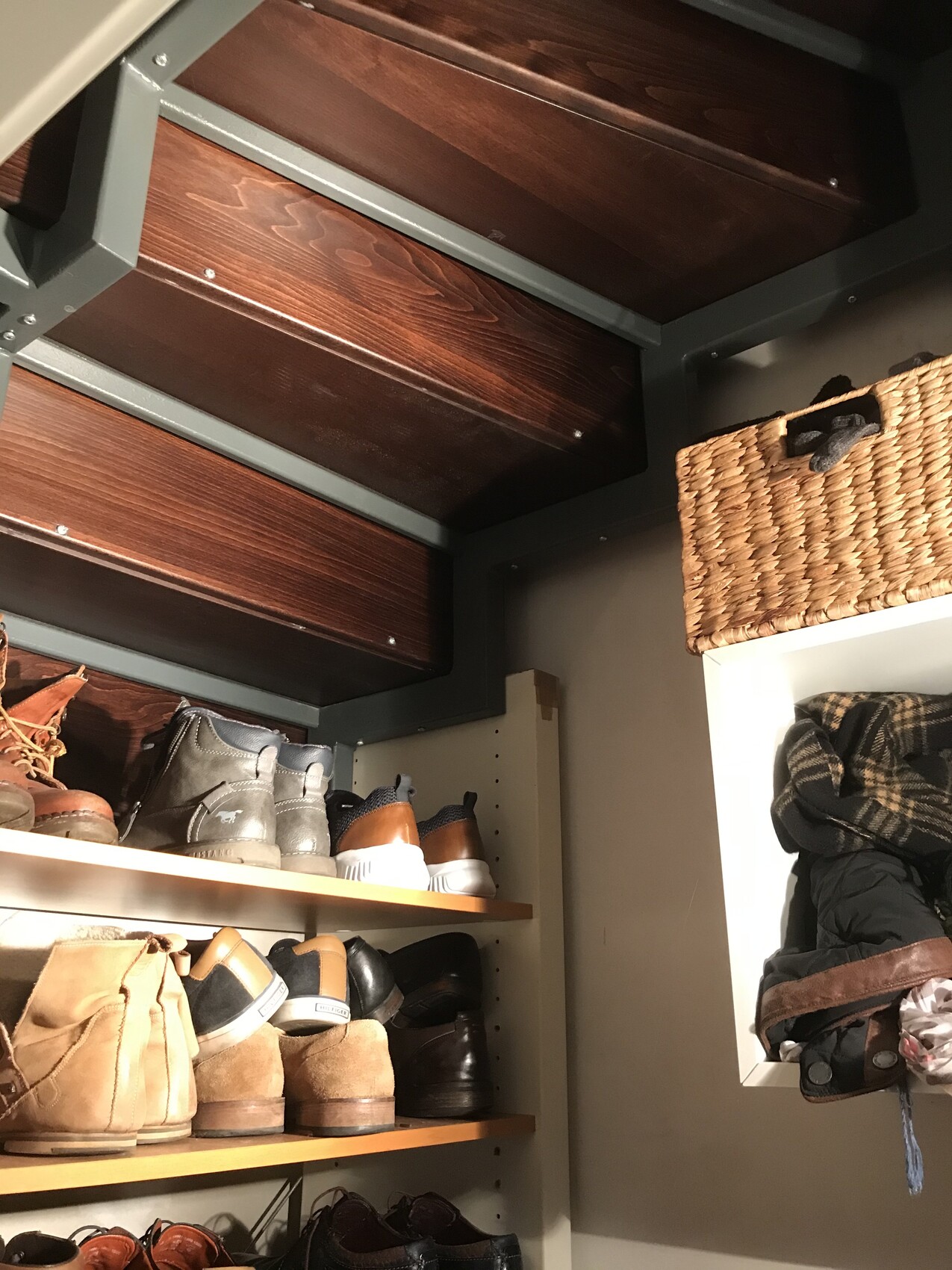Offenes Schuhregal mit Stiefeln, Boots und Sneaker; Korb oben rechts und Winterkleidung.