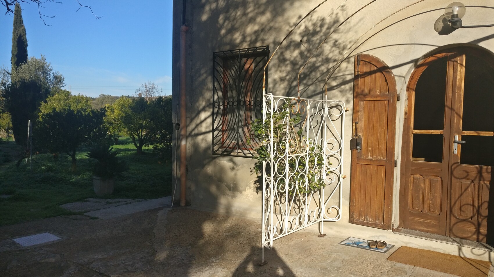 Außenansicht eines Hauses mit hölzernen Türen, weißem schmiedeeisernen Zaun und Garten.