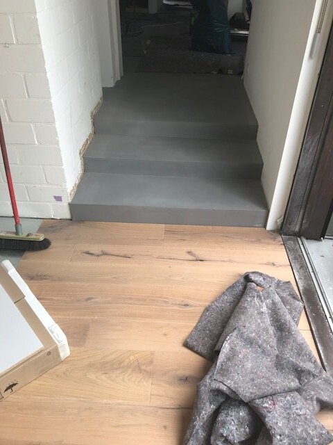 Heller Eingangsbereich mit grauer Treppe und Holzfußboden während Renovierung