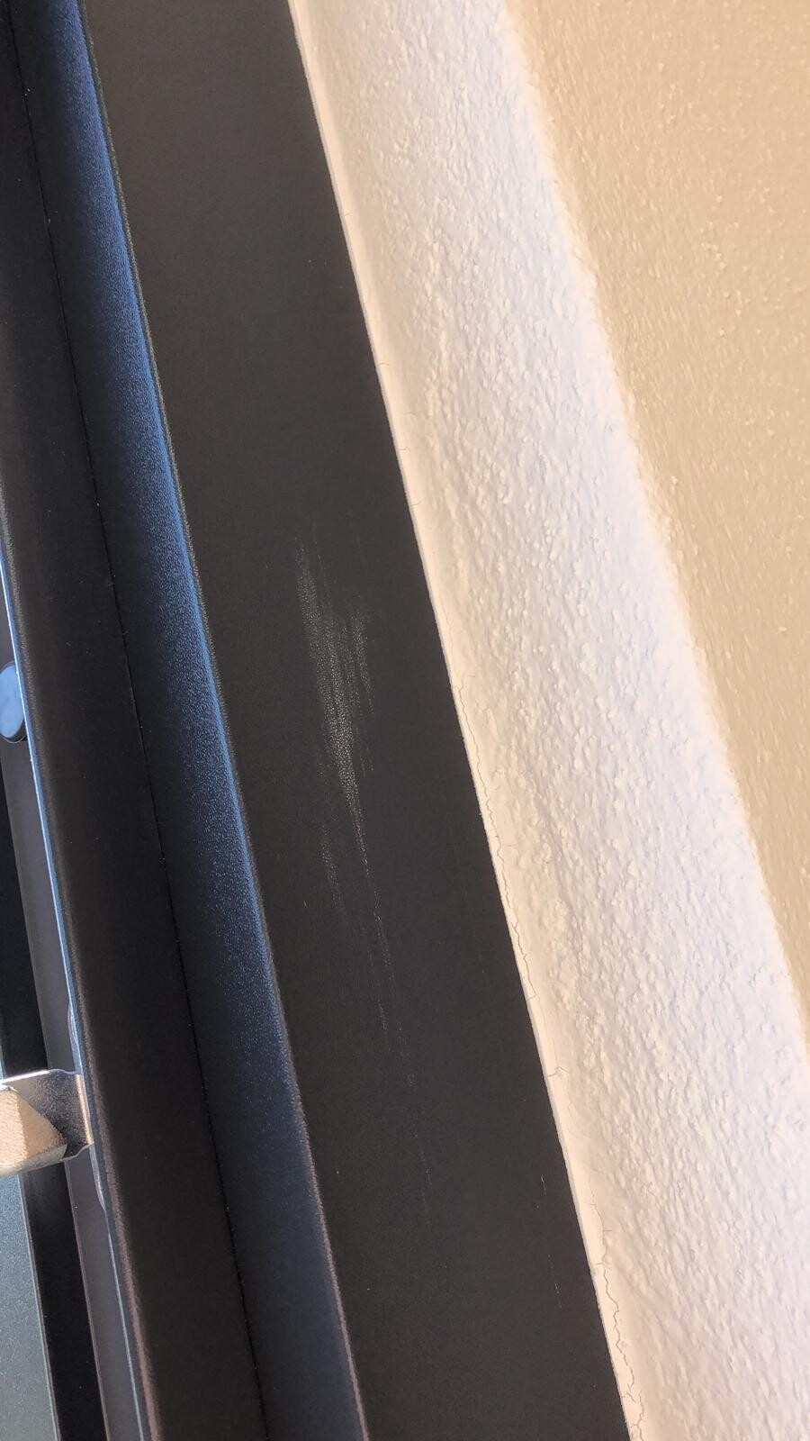 Nahaufnahme eines schwarzen Türrahmens mit Griff neben weißer Wand.