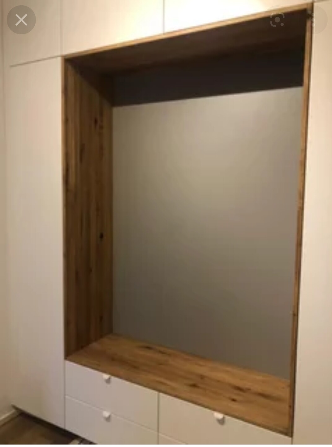 Offene Einbaunische mit Holzboden, linkem Holzpaneel, weißem Rahmen und drei Schubladen.