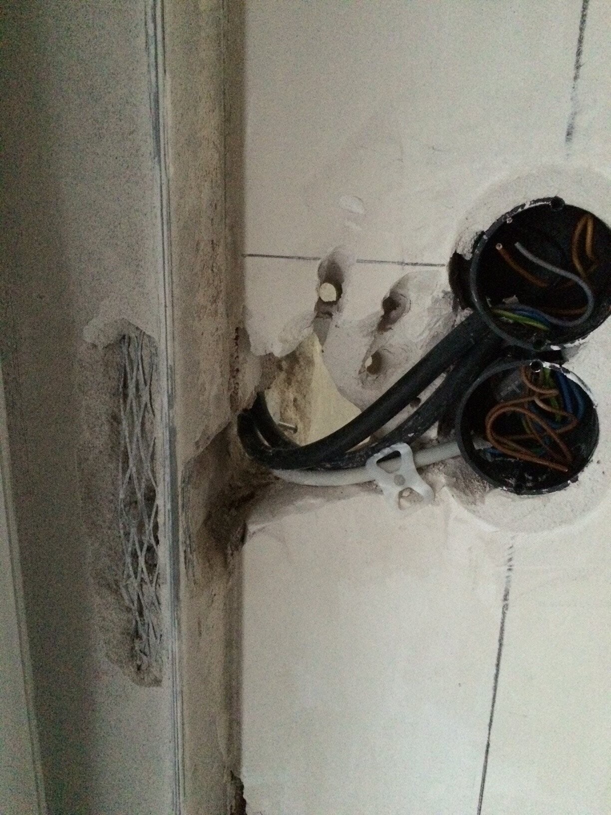 Offene Elektroinstallationen in Wand mit Kabeln und Leitungen im Rohbau