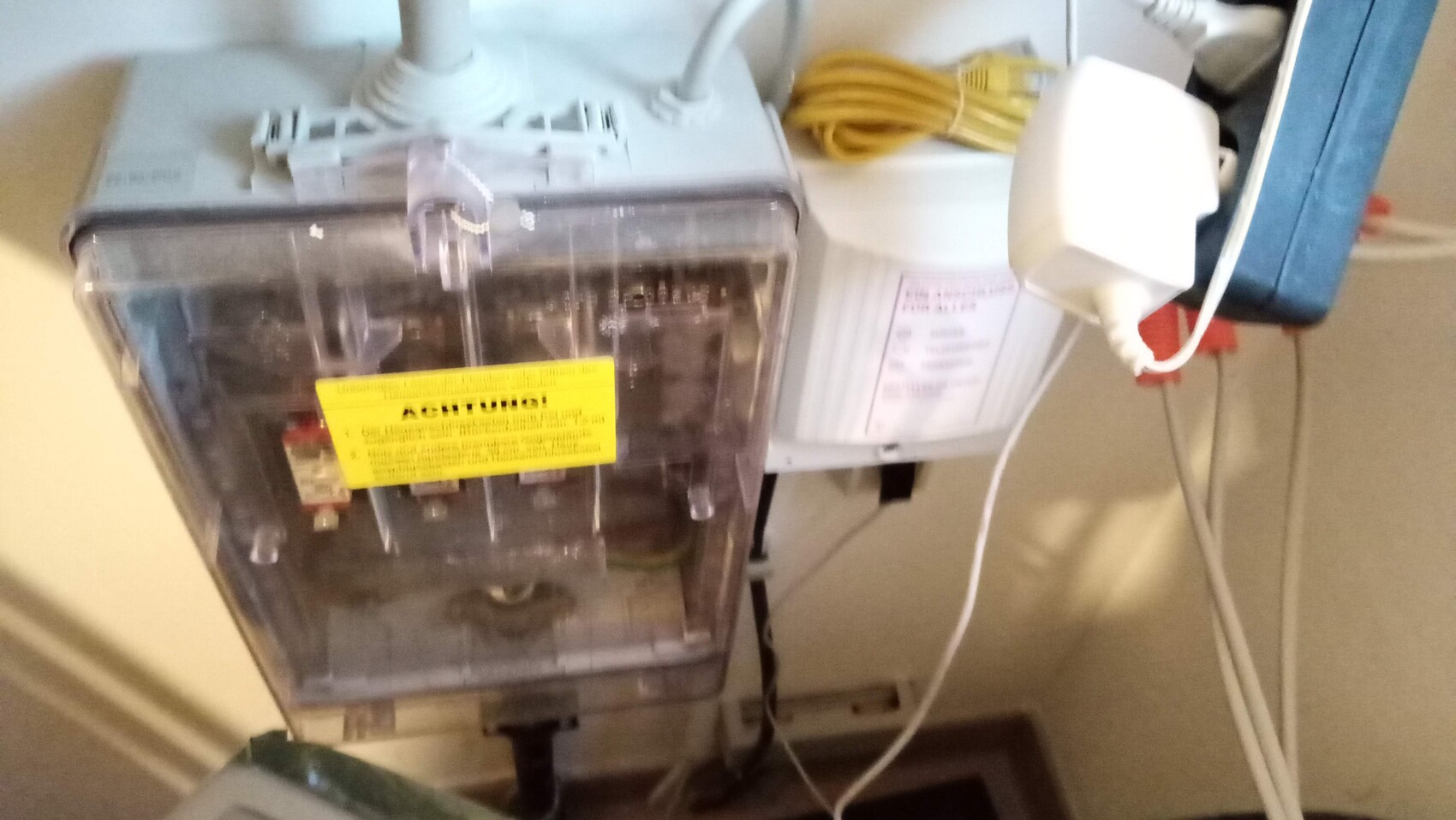 Nahaufnahme einer elektrischen Anlage mit gelben Warnaufkleber und Netzstecker