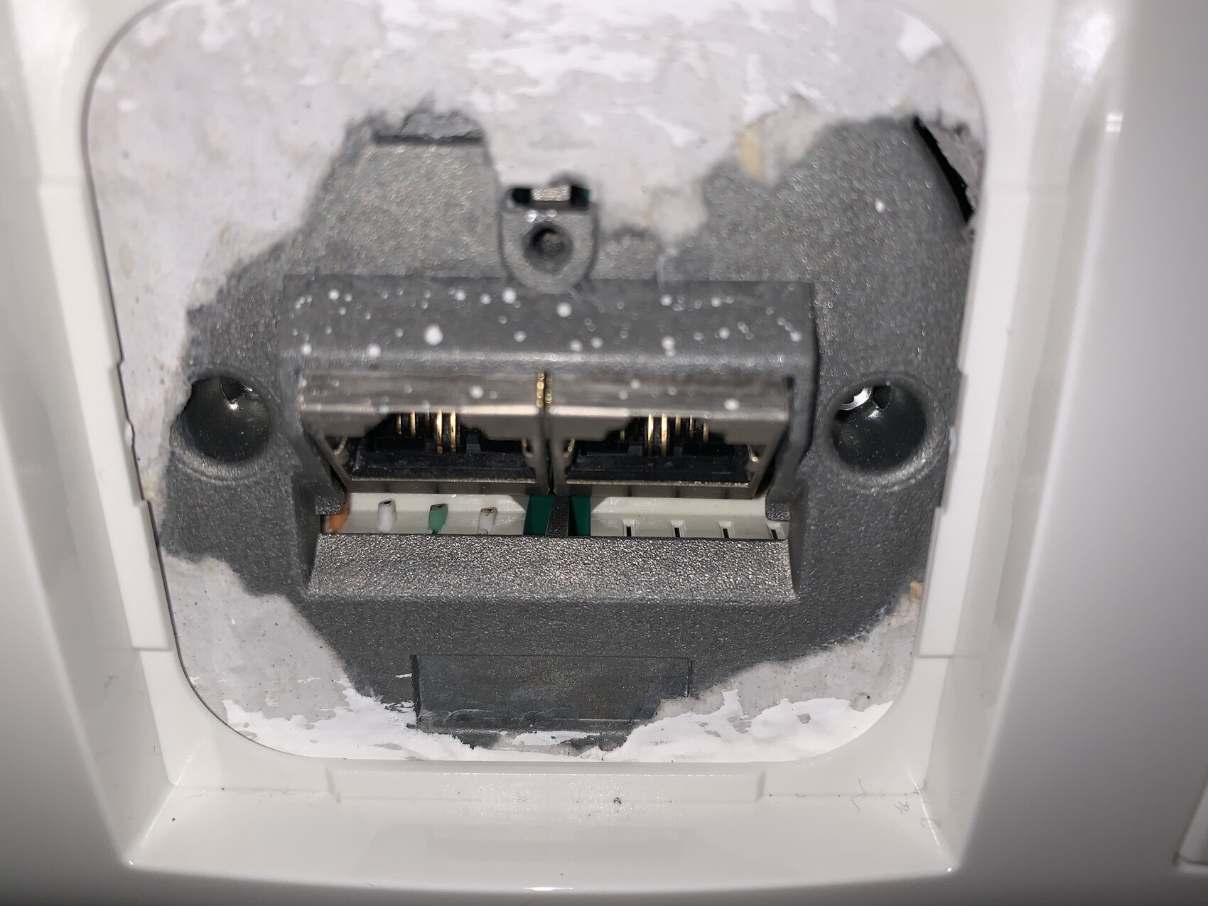 Nahaufnahme einer elektrischen Dose hinter der Wand mit Staub und Kontakten