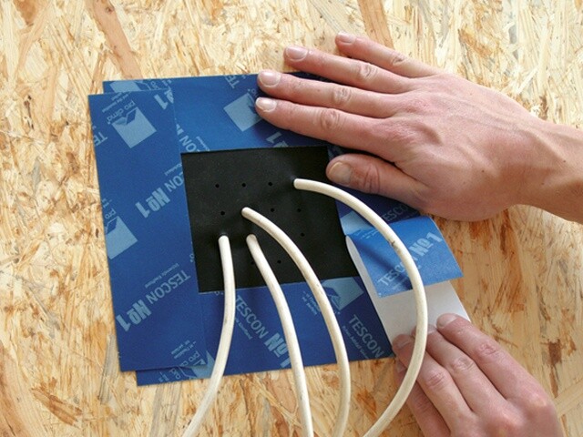 Hände legen Kabel bei Unterputz-Elektrik an einer Holzwand