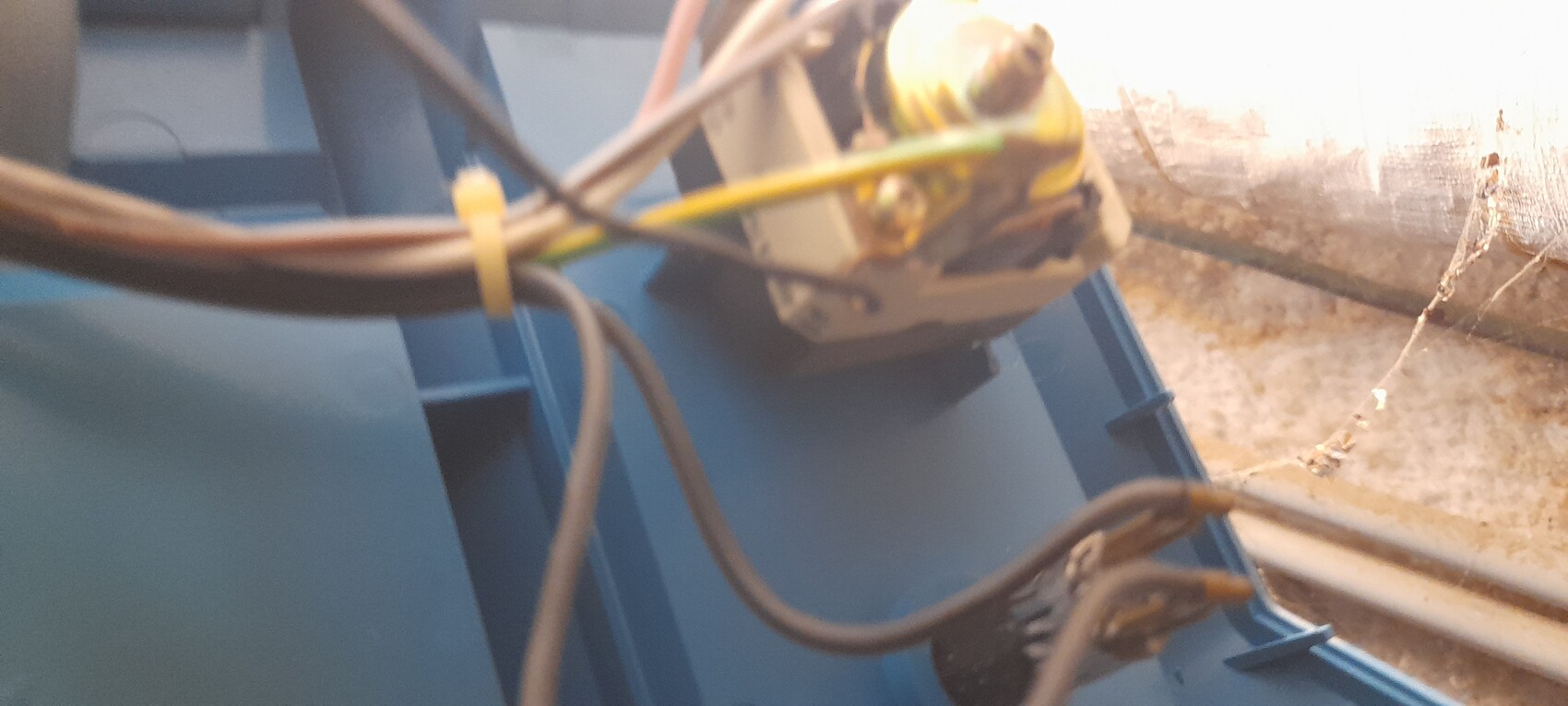 Nahaufnahme von Kabeln und einer Steckverbindung an einer blauen Metallkonstruktion im Innenraum.