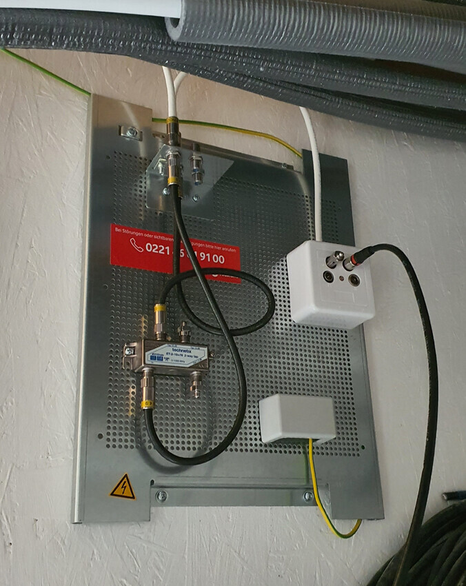 Elektroverteilungsplatte mit Kabeln, Koaxialanschlüssen, Erdung und Überspannungsschutz.
