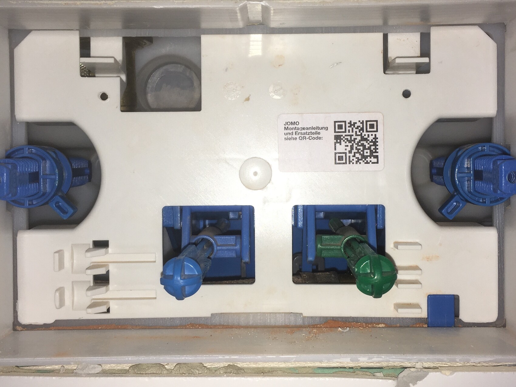 Nahaufnahme einer elektrischen Verteilerbox mit blauen Steckern und grünem Draht