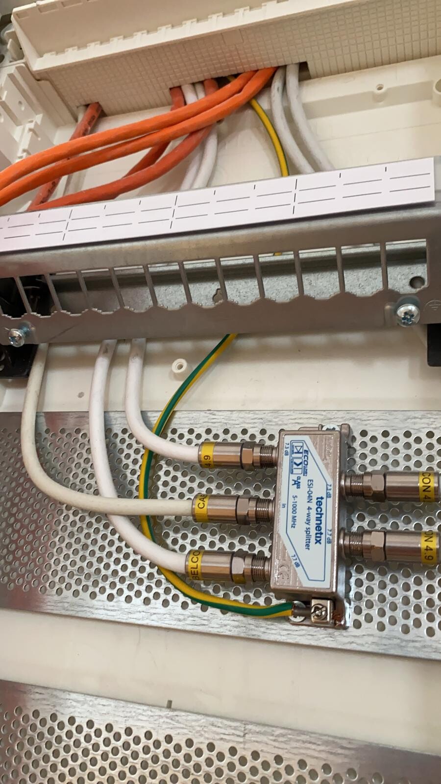 Elektrik-Schaltschrank: orange/weiße Kabel, Erdung, Metall-Verteiler mit Steckern.