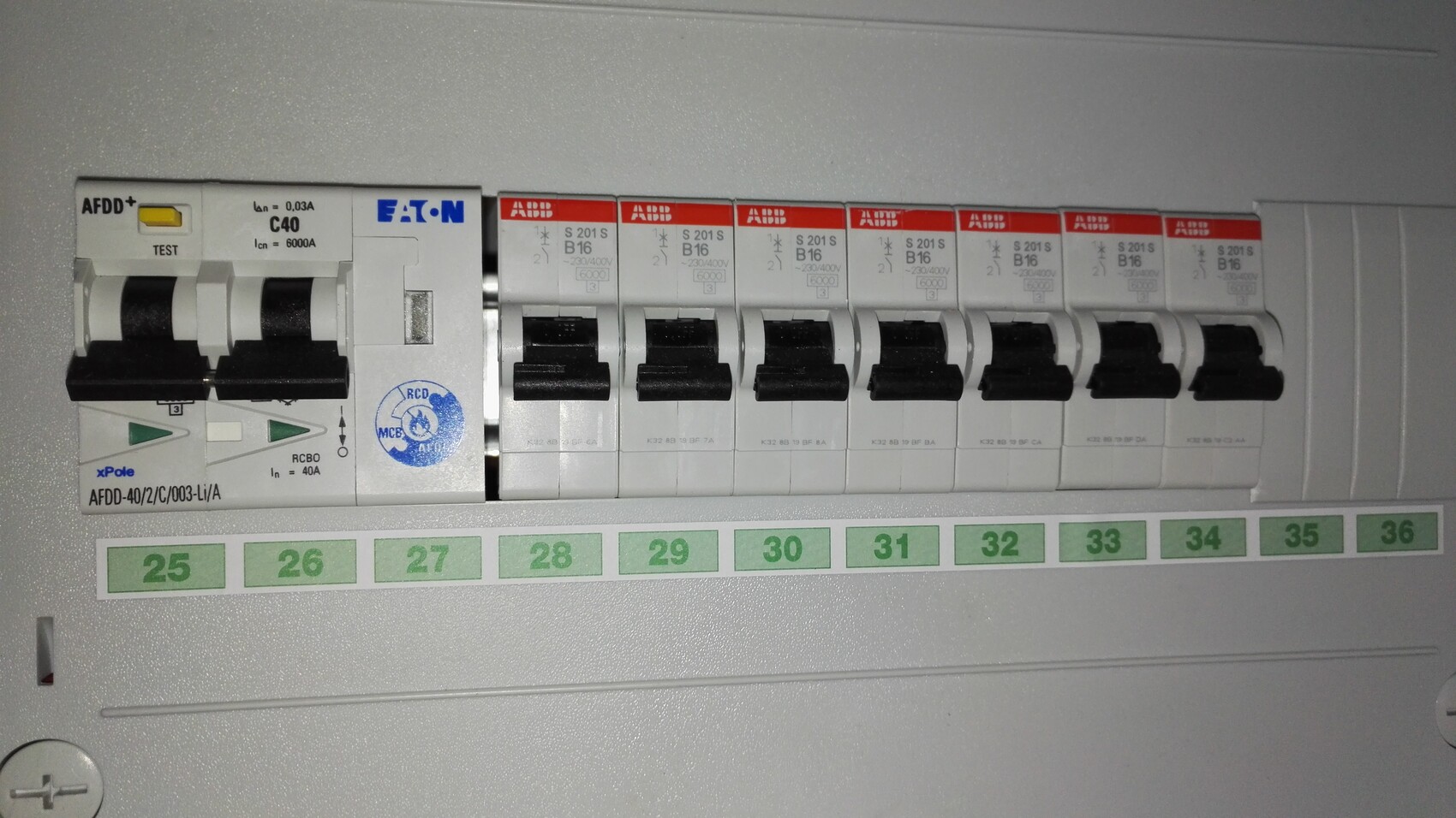 Verteilerschrank mit mehreren MCBs (ABB/EATON); grün markierte Zahlen 25–36 darunter.