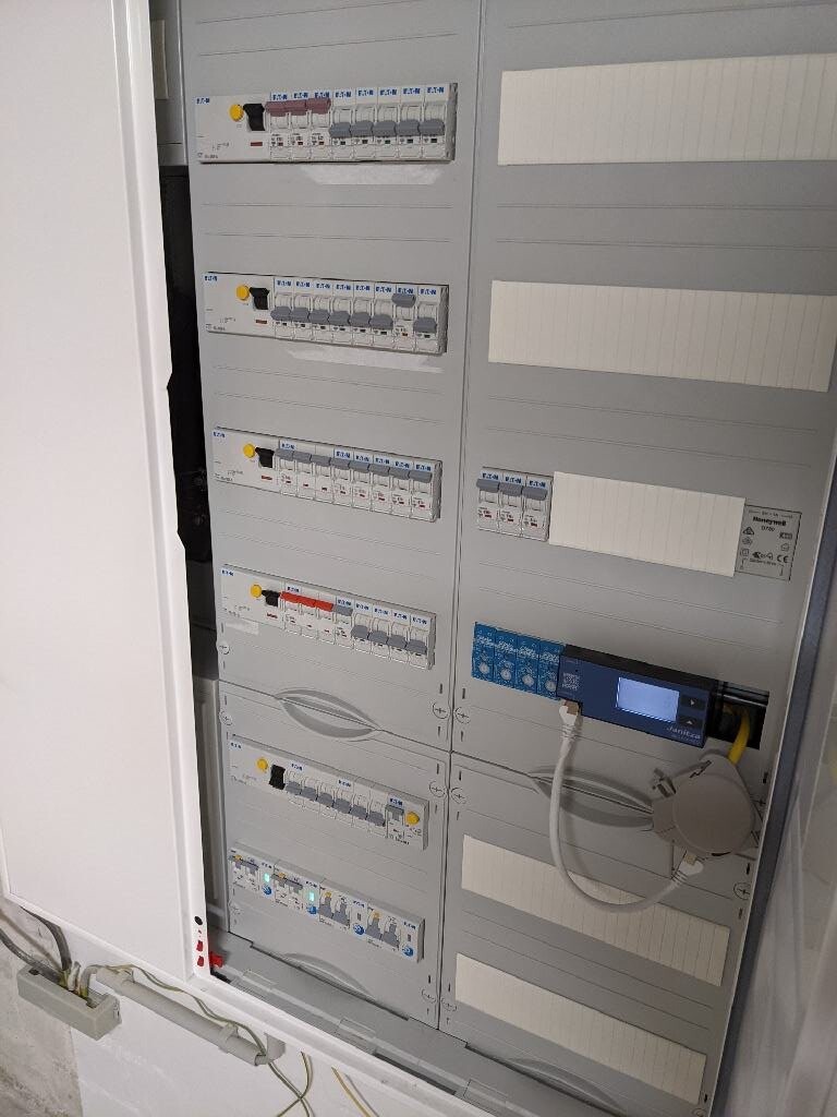 Elektrischer Schaltschrank/Verteiler mit vielen Sicherungen und blauem Messgerät mit Display