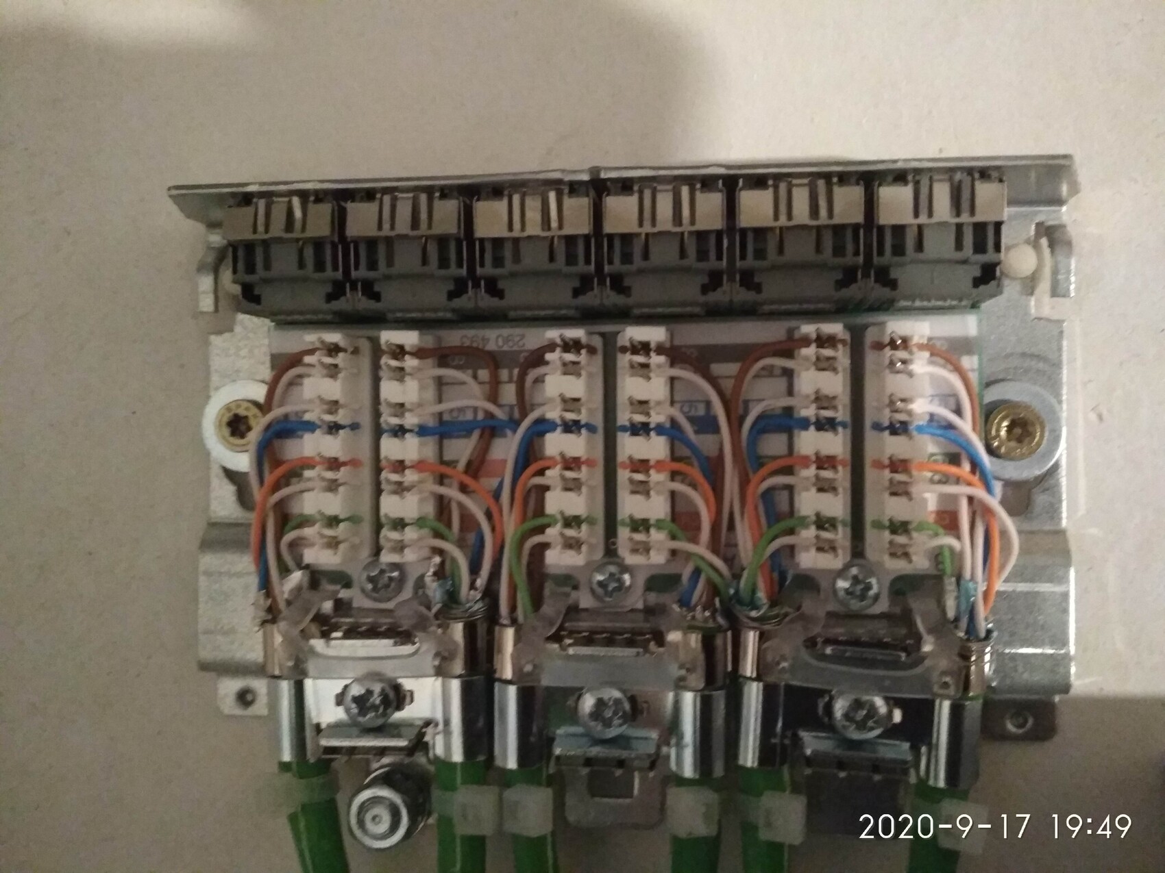 Elektrische Schalttafel mit mehreren Terminalblöcken und bunten Kabeln im Metallgehäuse.