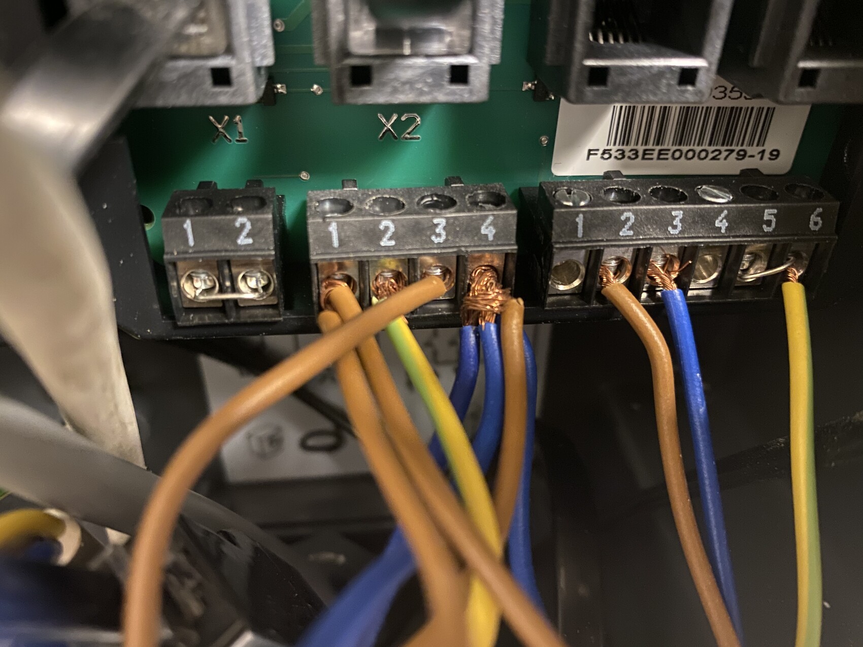 Nahaufnahme einer elektrischen Schalttafel mit Klemmen X1/X2 und mehreren Leitungen