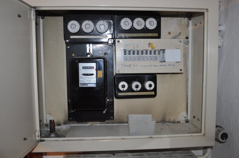 Alter Verteilerkasten für Strom mit Zählern, Sicherungen und Anzeigen in Wandnische.