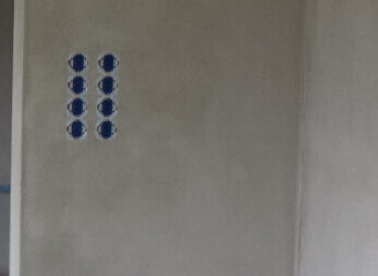 Sechs blaue runde Elektro-Dosen in einer Wand, Anordnung in zwei Spalten und drei Reihen