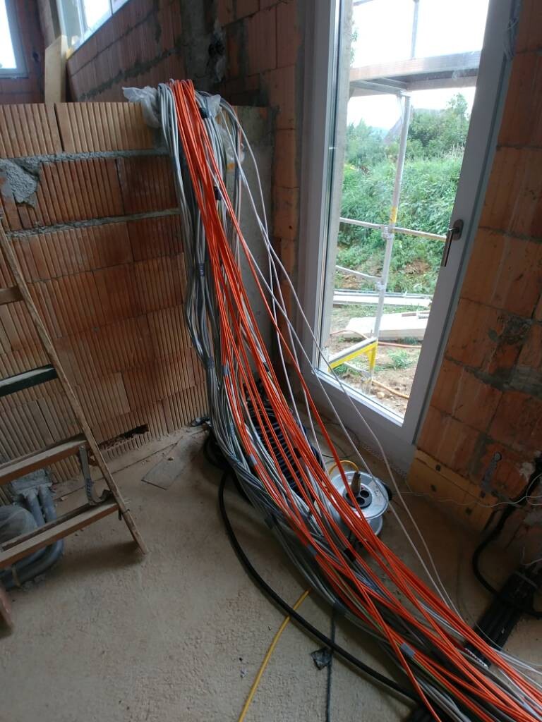 Innenraum einer Baustelle mit Kabelbündeln und offener Ziegelwand