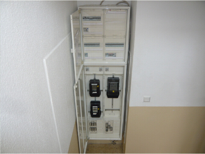 Offenes Verteilerschrank-System mit Zählern, Sicherungen und Messgeräten im Flur.