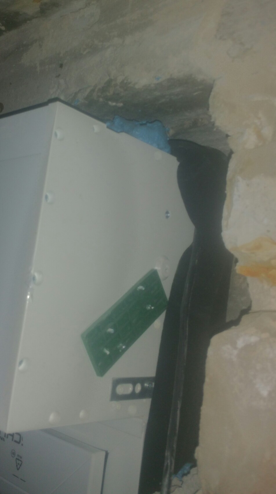 Elektrischer Verteilerkasten in einer Kellerwand mit unebener Putzoberfläche.
