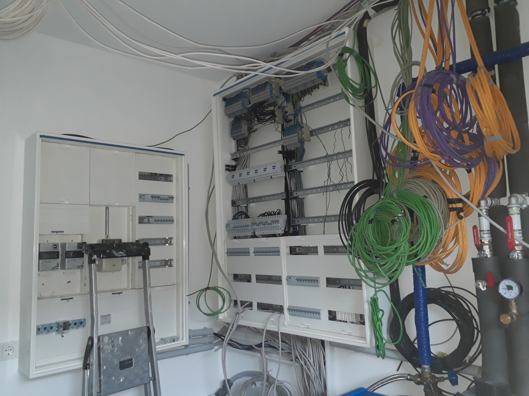 Elektrischer Verteilerkasten mit vielen Kabelbünden und bunten Schleifen im Technikraum.