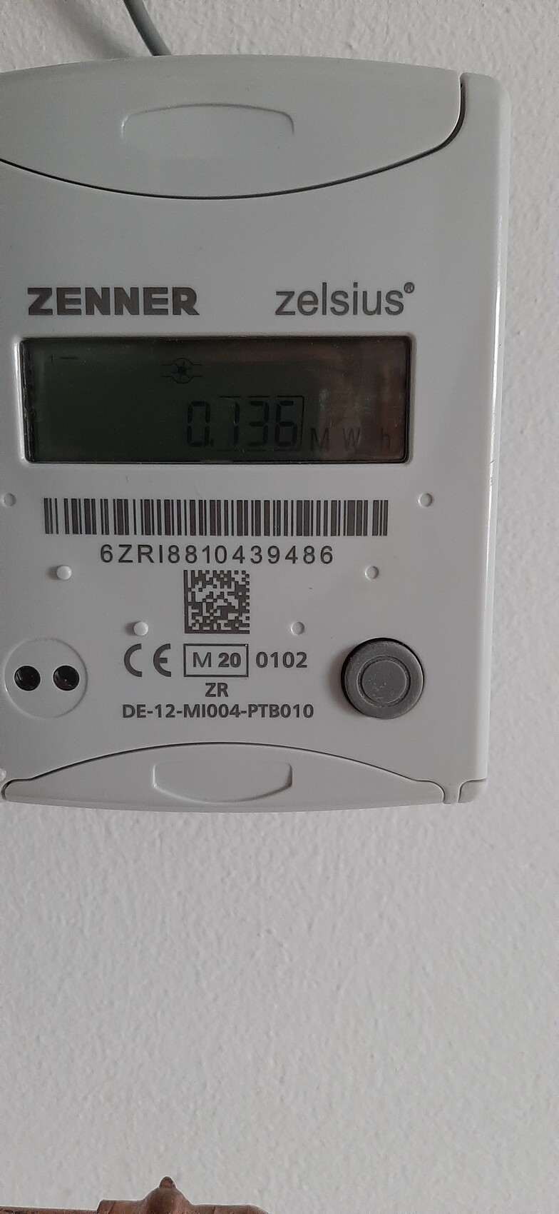Zähler der Firma Zenner (Zelsius) an weißer Wand; Display zeigt 0.136 MWh.