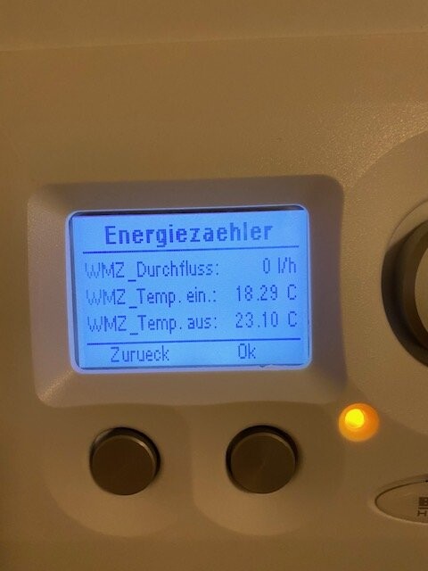 Energiemessgerät mit blauem Display, Durchfluss 0 l/h, Temp ein 18,29 °C, Temp aus 23,10 °C, orange LED.