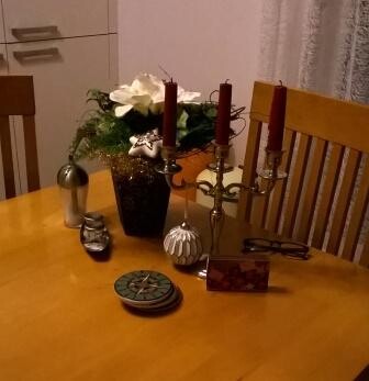 Esstisch mit Blumenvase, Kerzenständern und dekorativen Gegenständen vor Holzstühlen