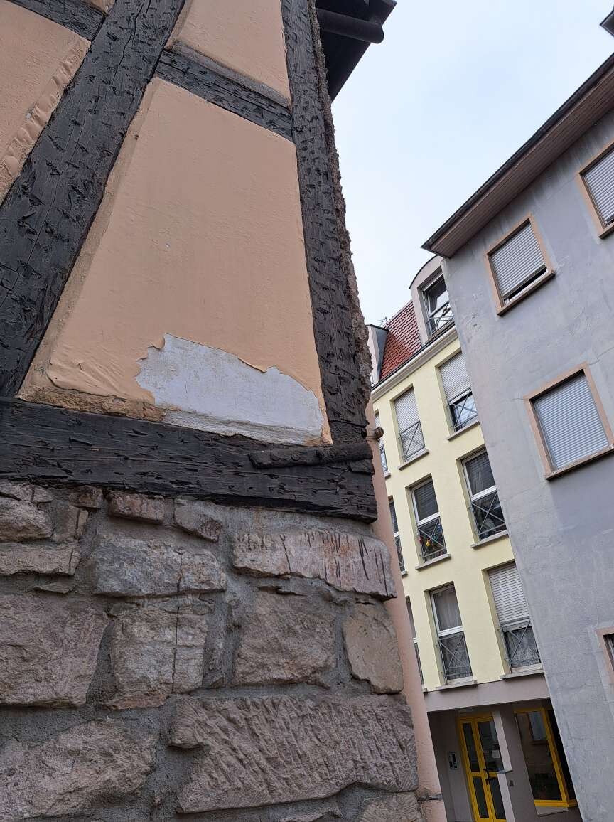 Fachwerkhaus mit Steinfundament neben modernen Gebäuden