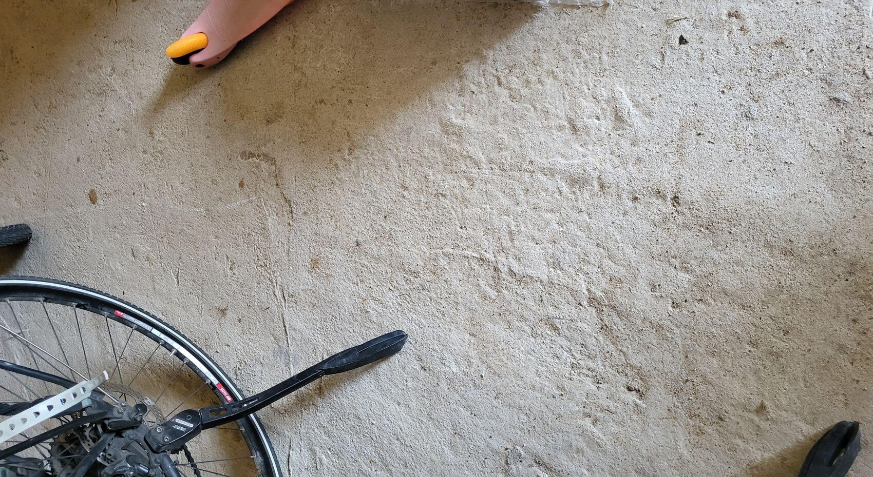 Fahrrad auf staubigem sandigen Boden, nahe Hand mit orangefarbenem Werkzeuggriff sichtbar