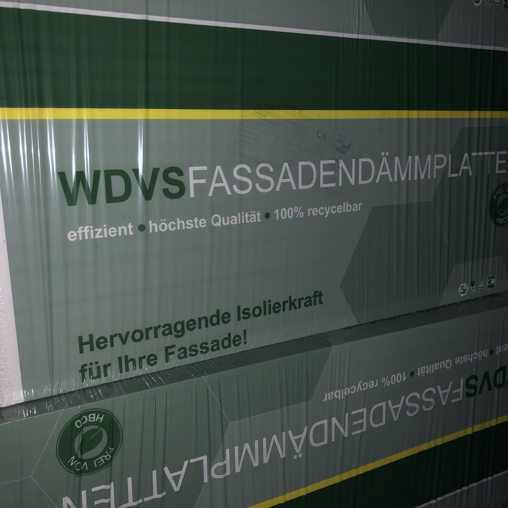 Grüne Verpackung von WDVS-Fassadendämmplatten mit Hinweis auf Effizienz und Recycling.