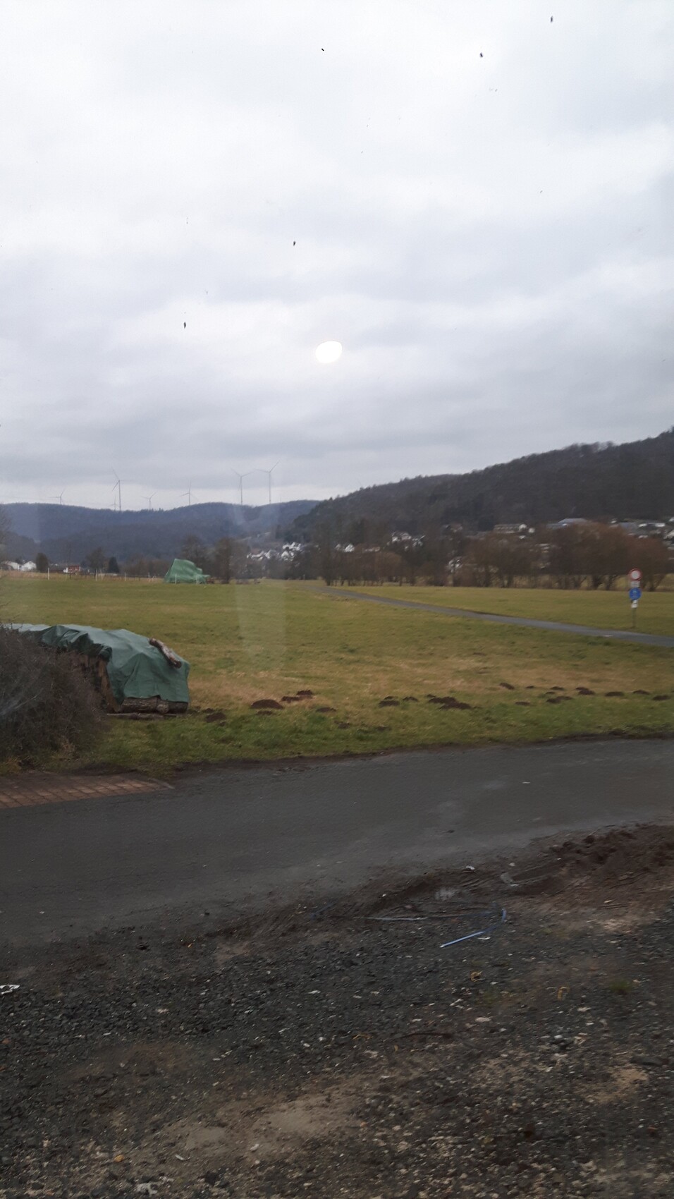 Feldlandschaft mit Windkraftanlagen im Hintergrund und Baustellenmaterialien vorne.