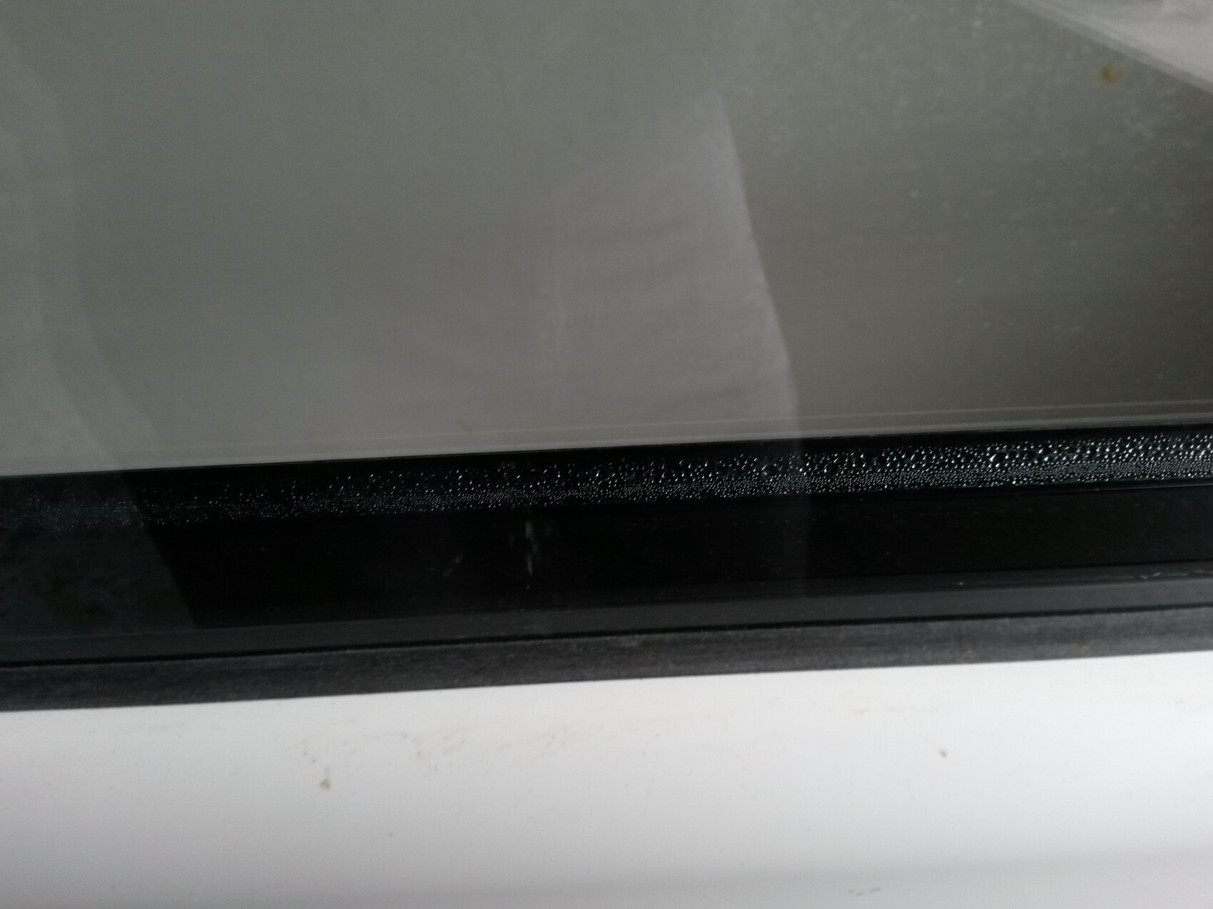 Nahaufnahme eines Fensterrahmens mit schwarzer Dichtungsleiste und Glasscheibe