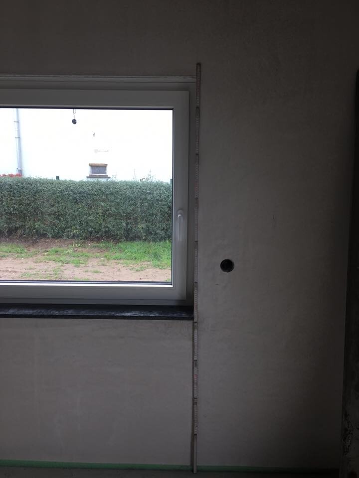 Innenraum einer Baustelle mit Fenster installiert, Messlatte an Wand, roher Putz.