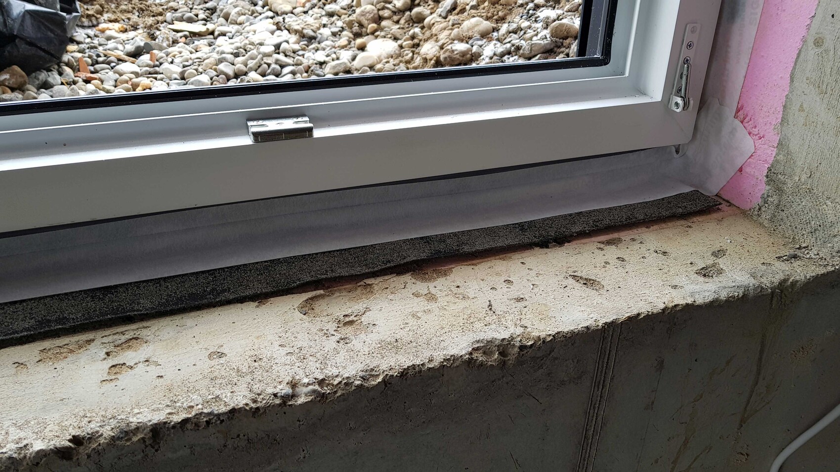 Fensterrahmen im Rohbau mit Betonfensterbank und pinker Dämmung am Mauerwerk