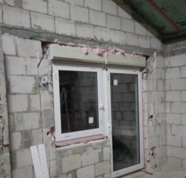 Unfertiges Fenster im Rohbau einer Steinwand, Bauarbeiten sichtbar.