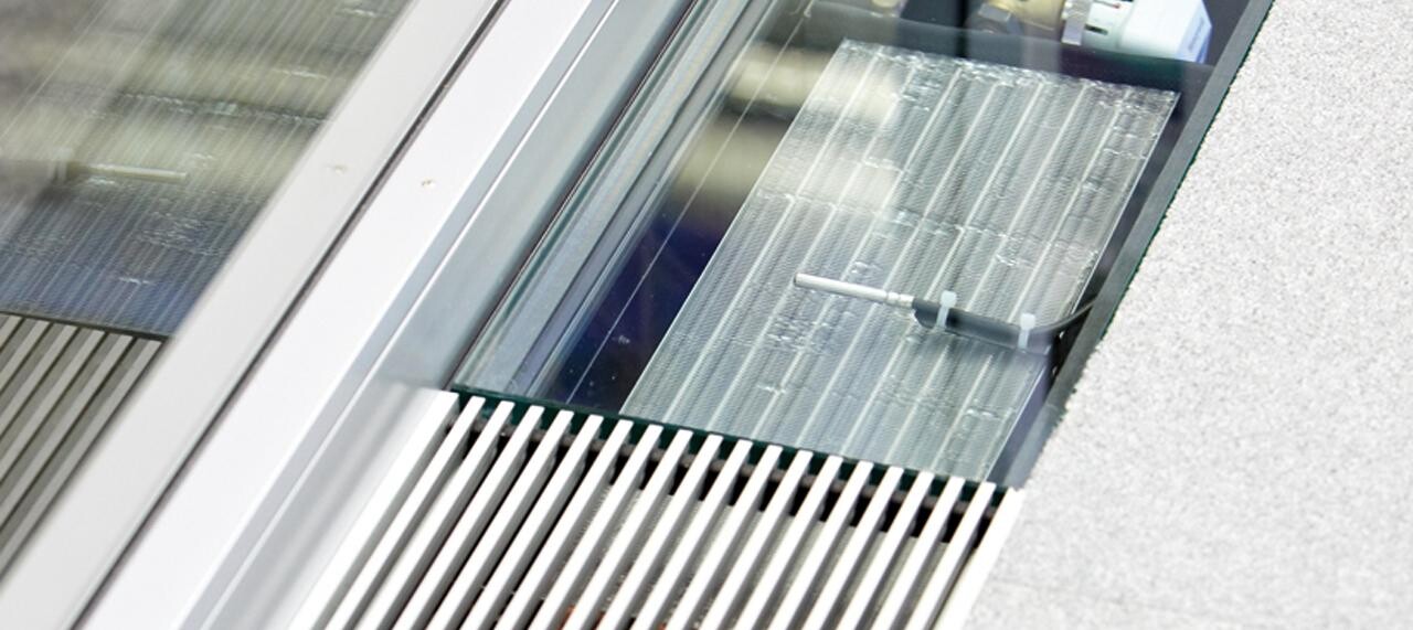Nahaufnahme eines Fensters mit Glasfront und Lamellenrahmen an einer Gebäudefassade