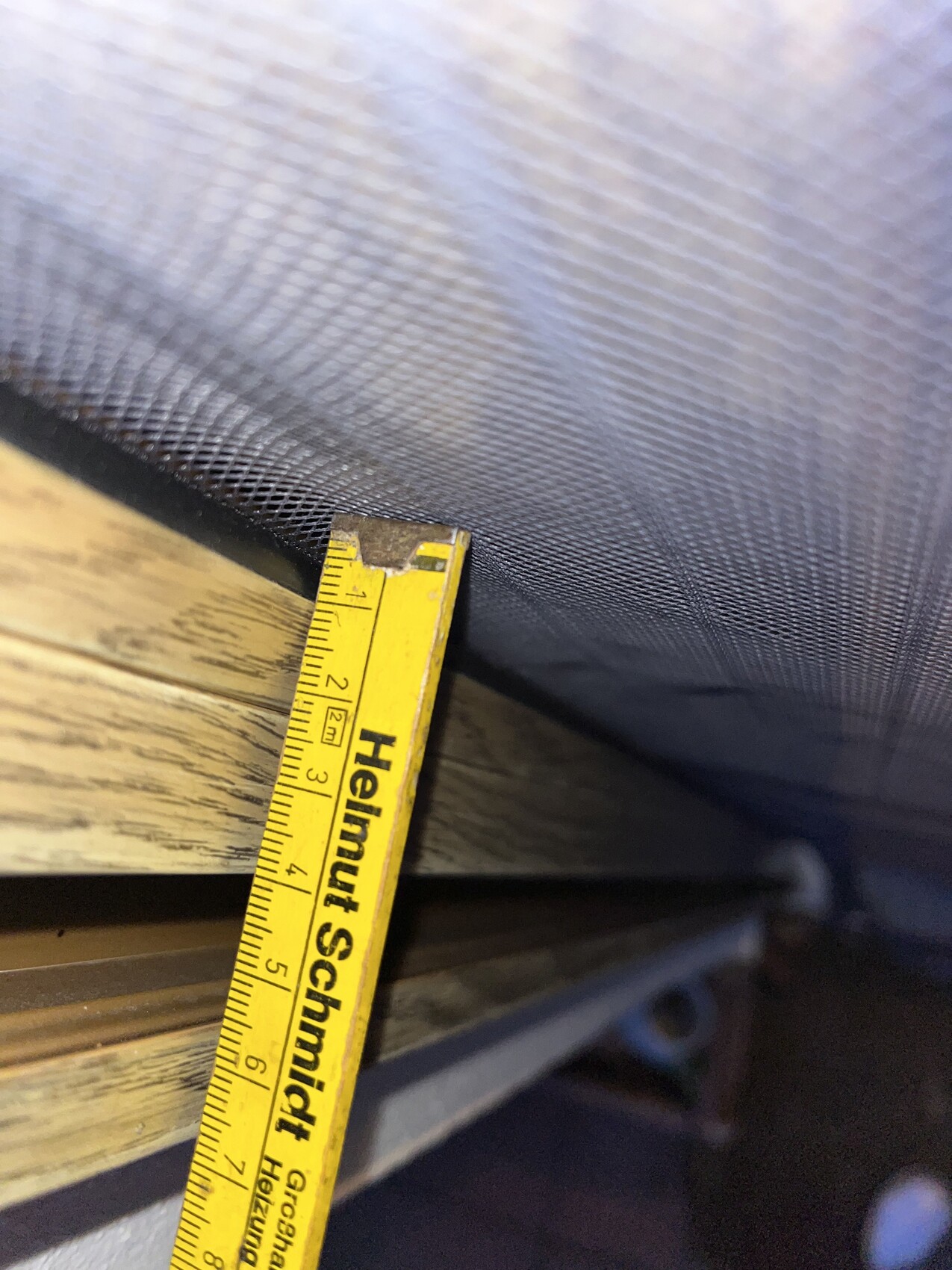 Nahaufnahme eines gelben Maßbands neben einem Fenstergitternetz