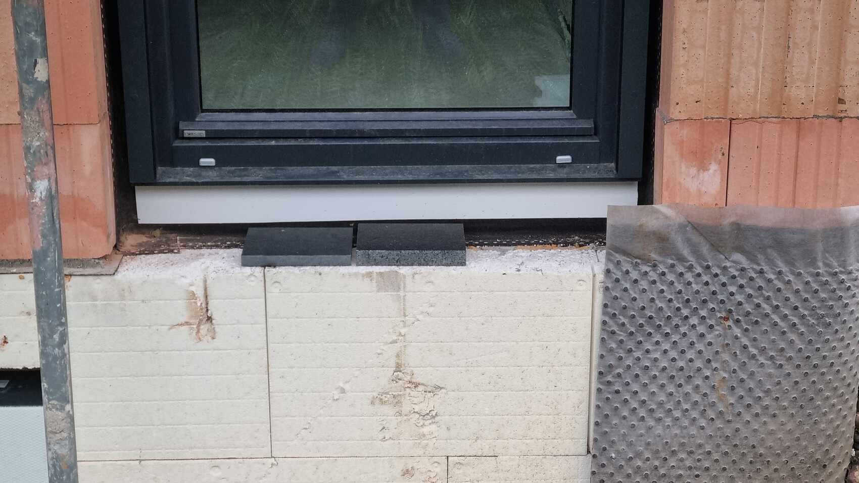 Fensterrahmen in roher Außenwand mit Steinverblendung und Bauarbeiten