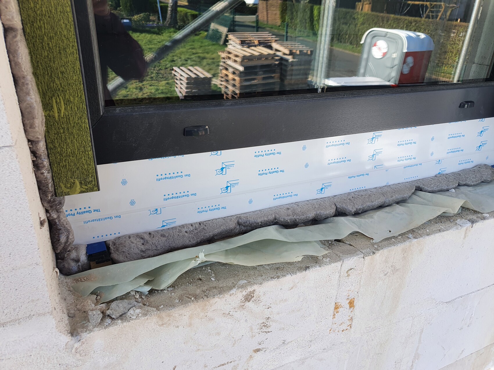 Fensterrahmen wird auf einer Baustelle installiert, Schutzfolie und Dämmung sichtbar