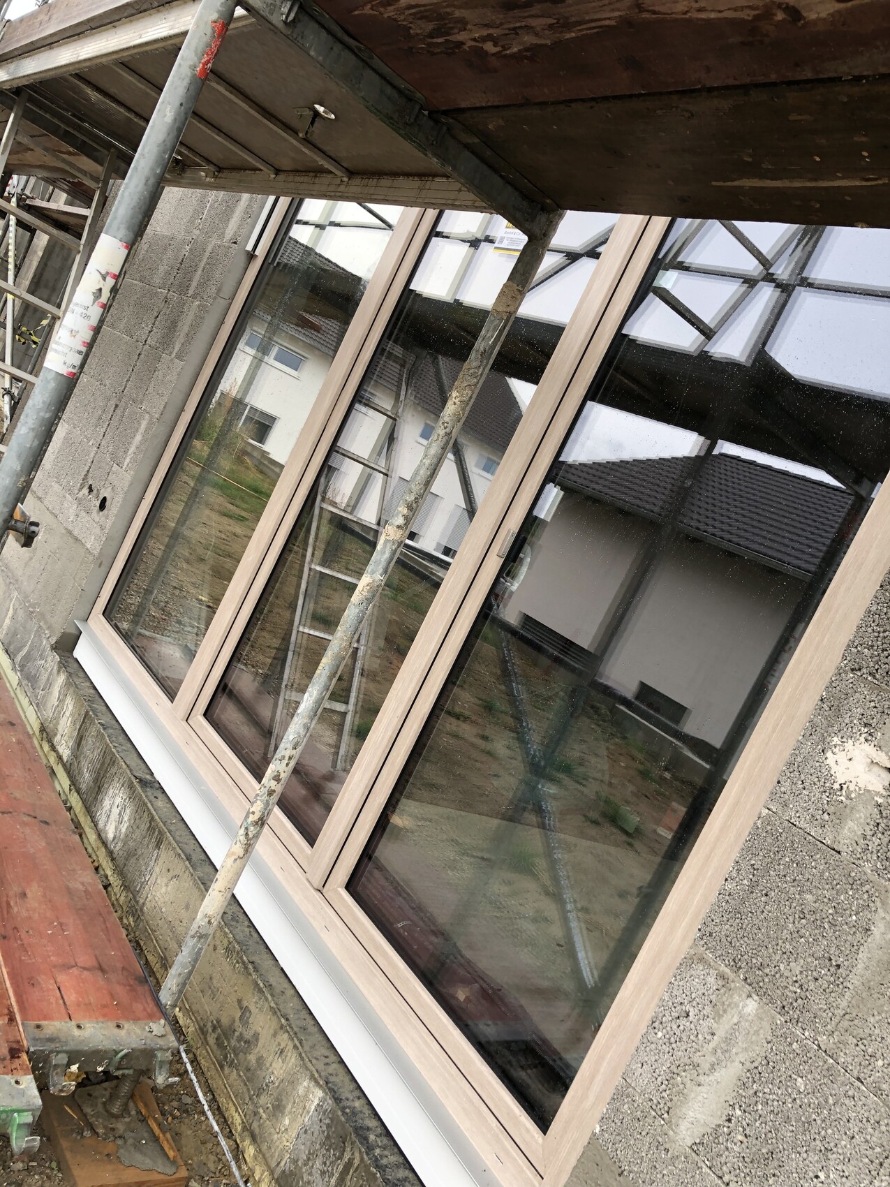 Neu installiertes Fenster im Rohbau mit Gerüst und Schalung sichtbar