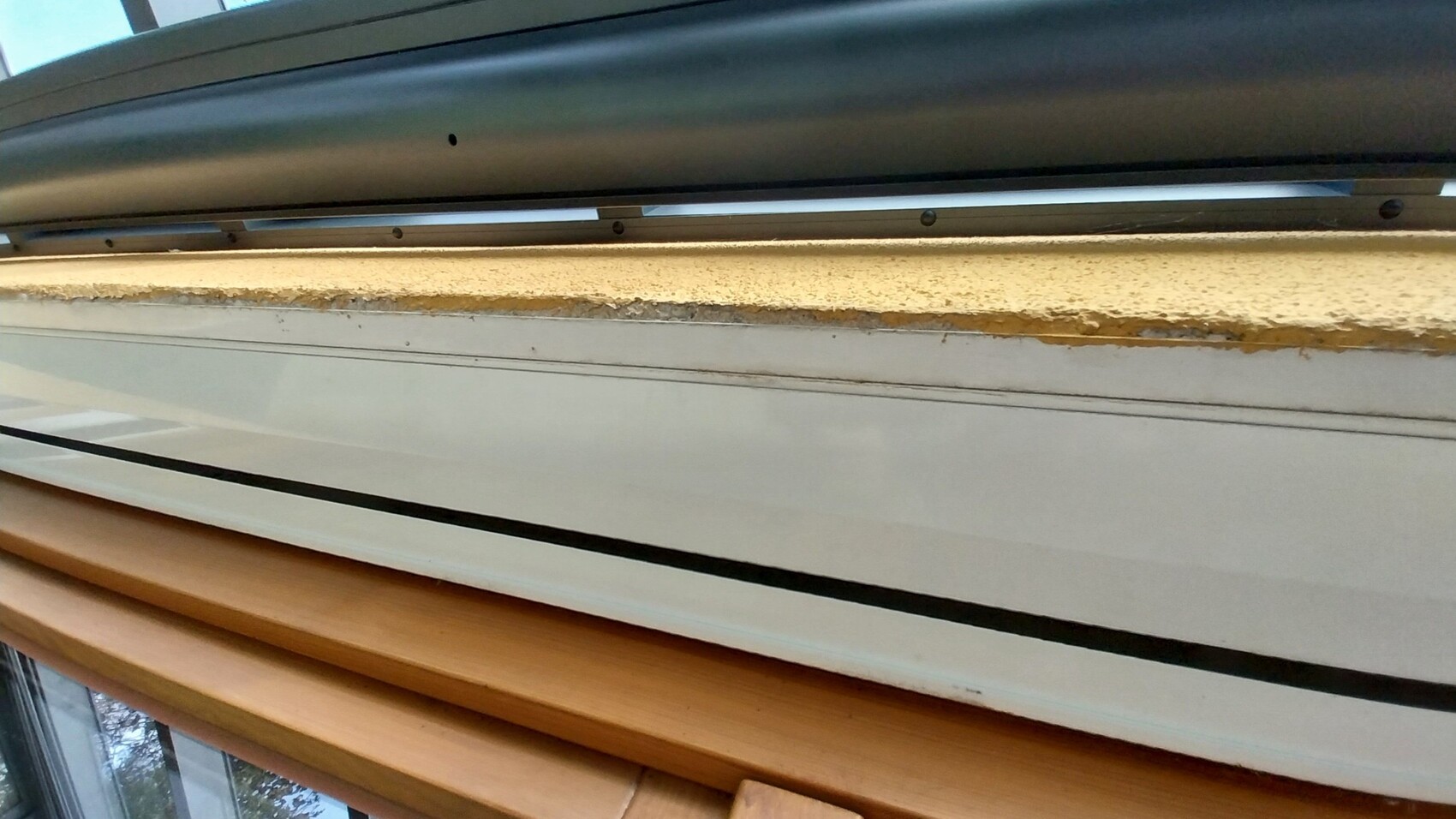 Nahaufnahme eines Fensterrahmens mit beschädigter Dämmung und Putzabplatzungen