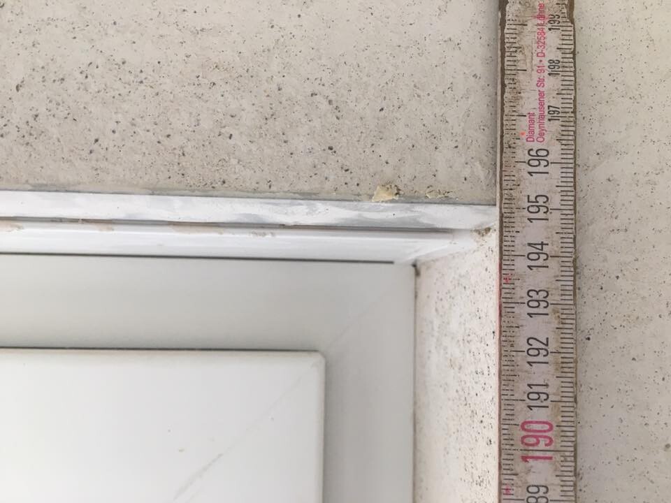 Nahaufnahme eines weißen Fensterrahmens mit Maßband bei Bauarbeiten