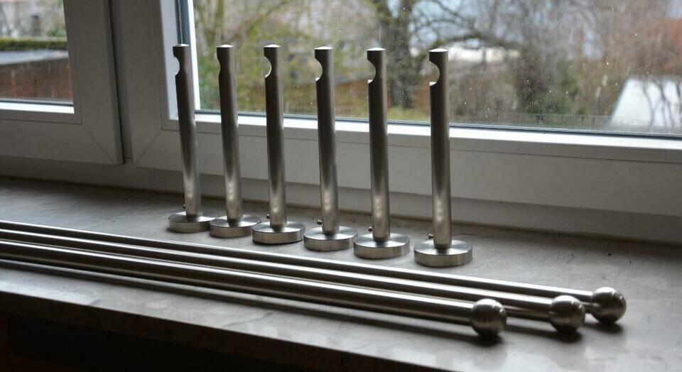 Mehrere silberne Metallstifte mit runden Köpfen stehen auf der Fensterbank.