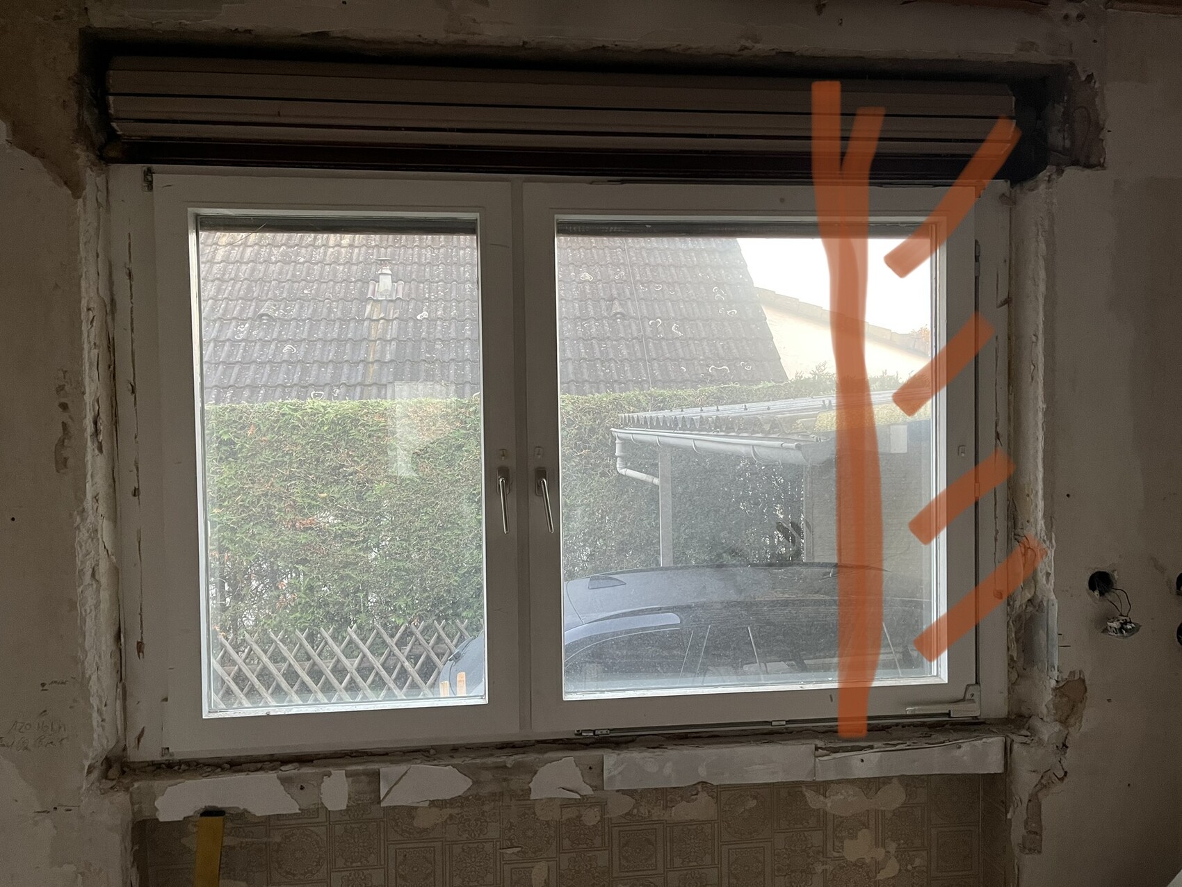 Innenraum mit weißem Doppelfenster, orange Markierung am Fenster, Blick nach draußen aufs Auto.