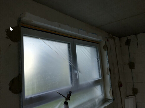 Unfertiges Zimmer mit Fenster; Putzarbeiten am Rahmen, Sprühgerät vor der Scheibe.