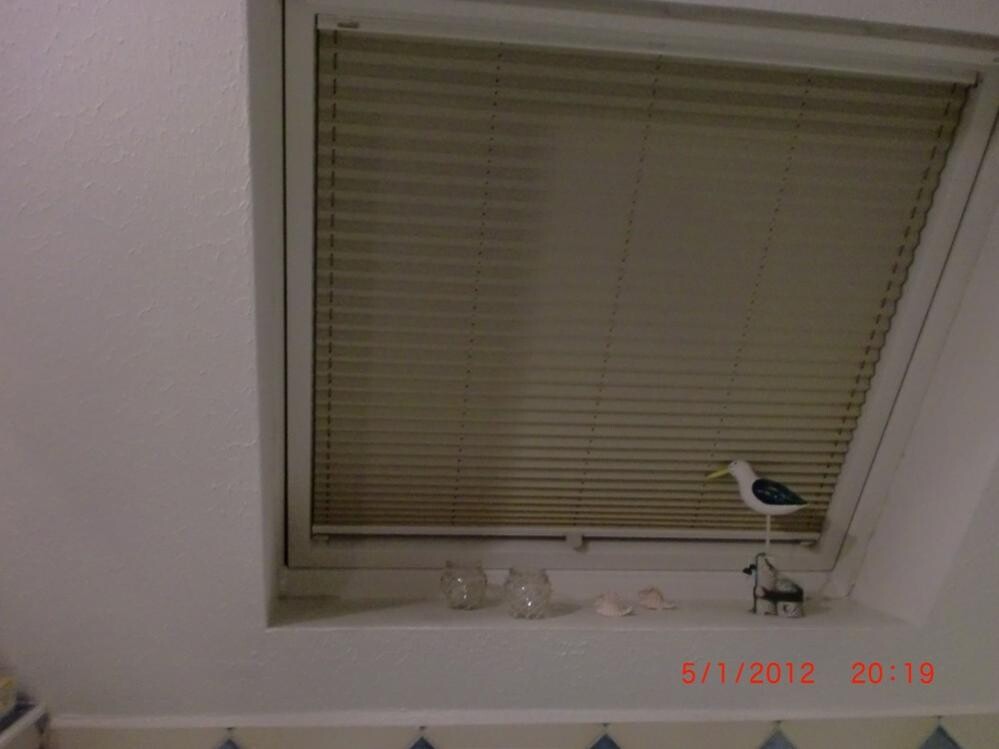Fenster mit geschlossenem Rollladen, Fensterbank mit Dekorfiguren und Datumstempel